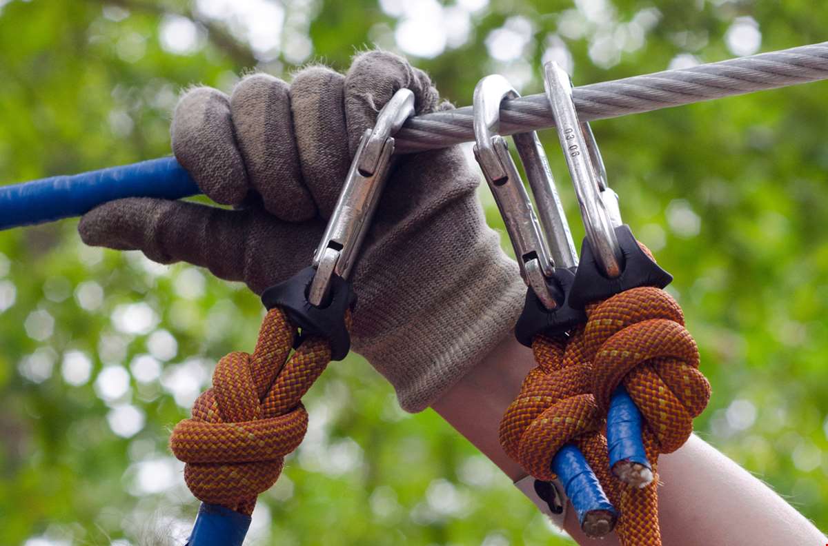Hånd med hanske griper tak i zipline.